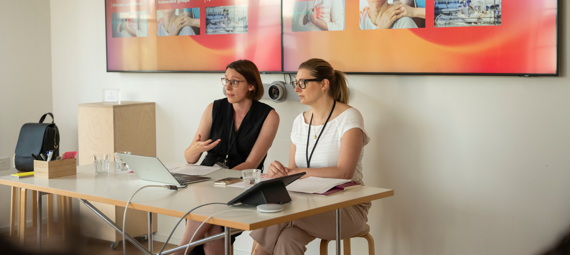 Two women sitting together, using laptops.